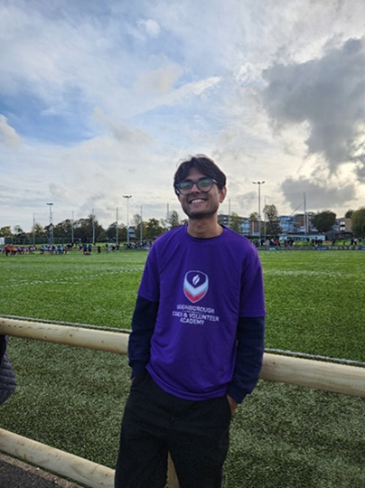 Student standing in front of rugby pitch